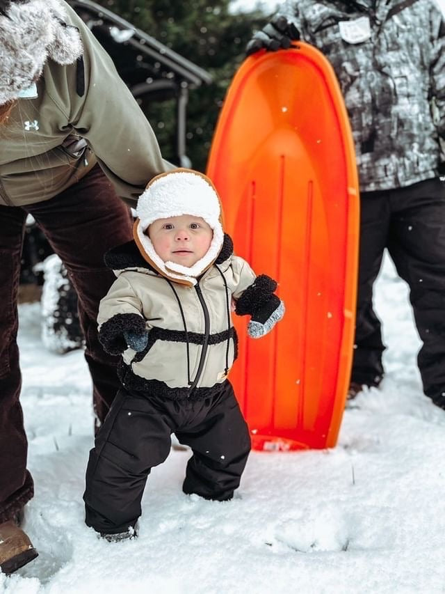 Toddler boy in the snow dressed in his SnuggleZip jacket, warm, accessible, and made for play.